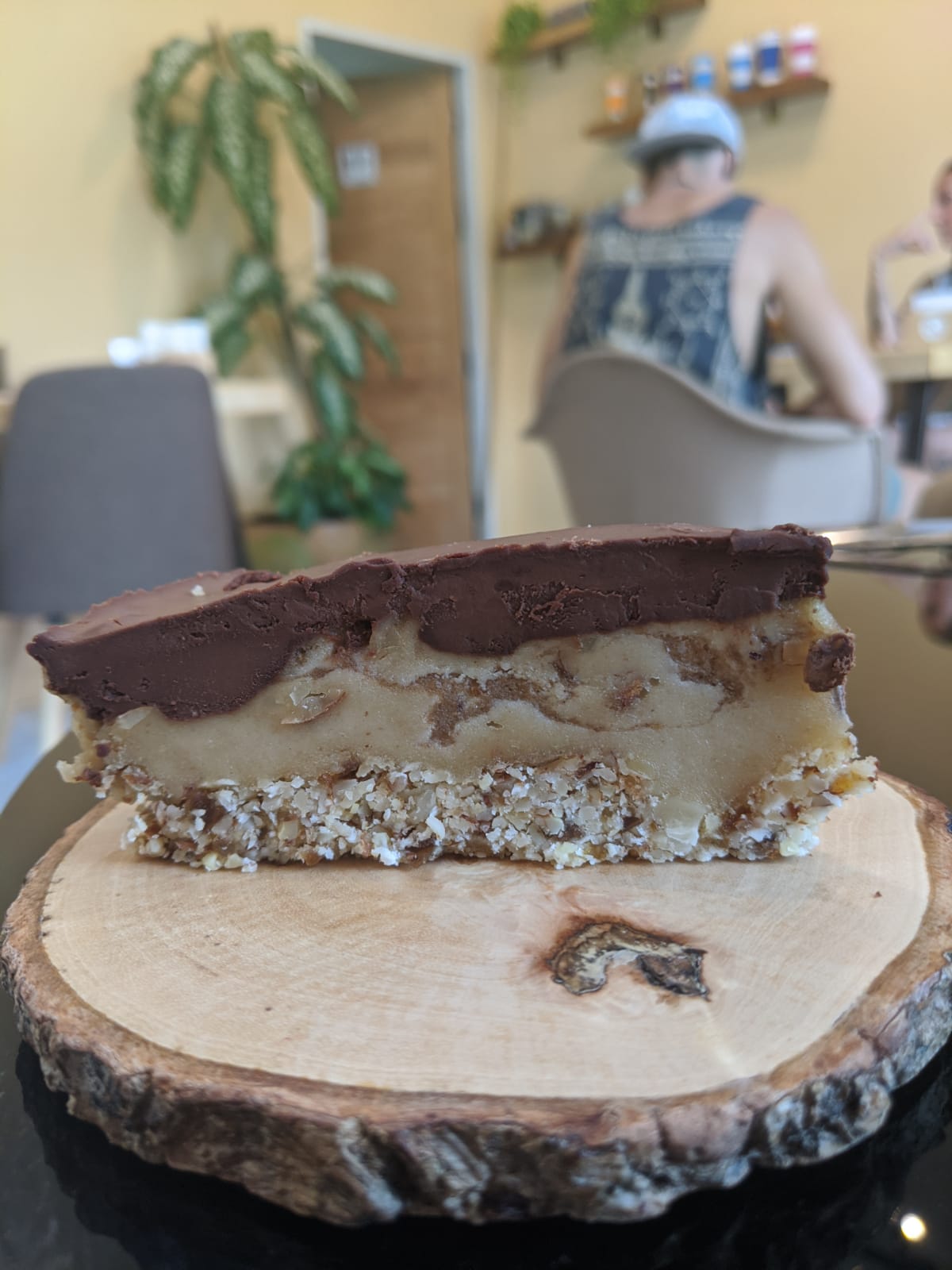 A slice of layered vegan cake on a wooden board at Deli Devi, Koh Phangan