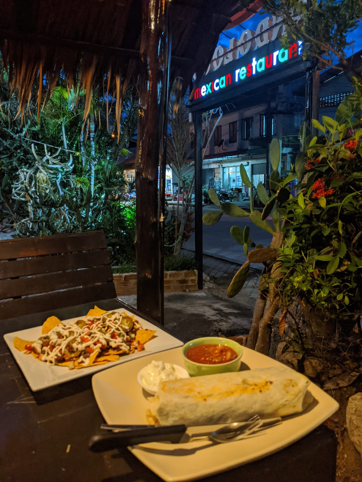 Vegan nachos and a burrito on an outdoor table at night at Ando Loco, Koh Phangan