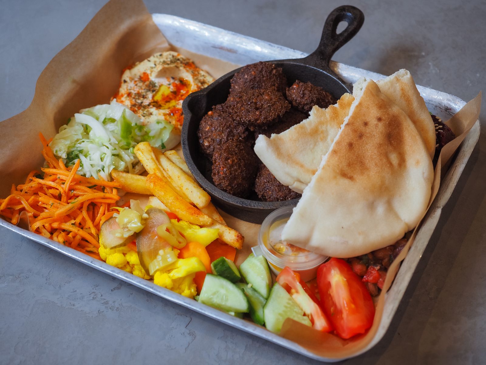 Falafel with pita bread, fries and fresh salad on a serving tray