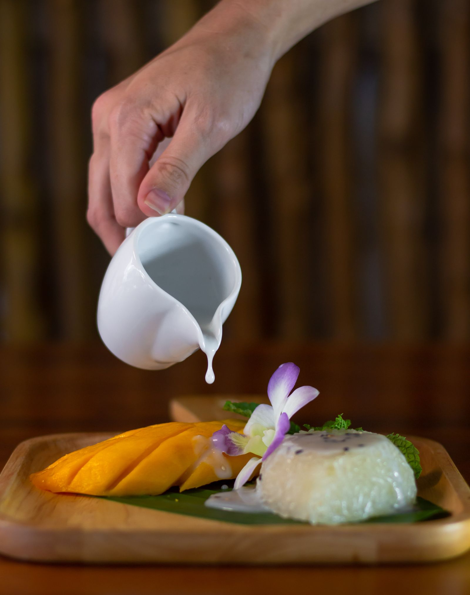 Thai mango sticky rice with coconut milk being poured over it