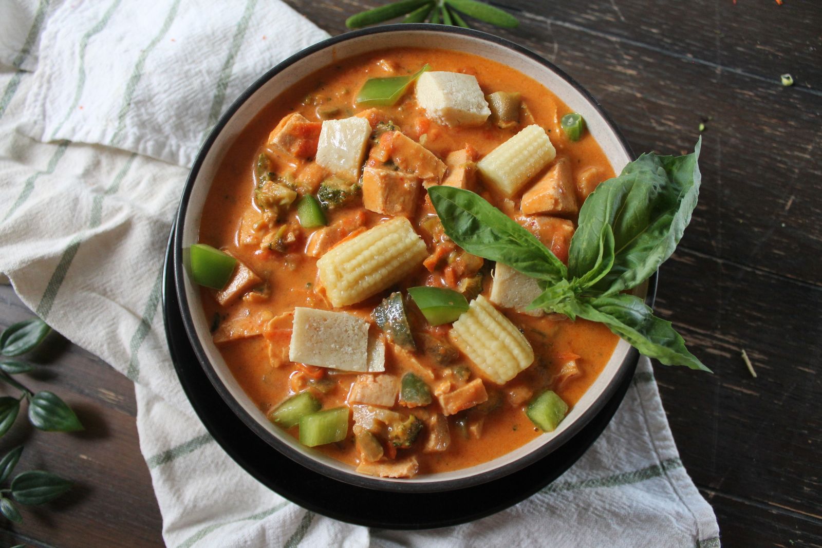 Thai red curry with tofu, baby corn and fresh basil in a bowl